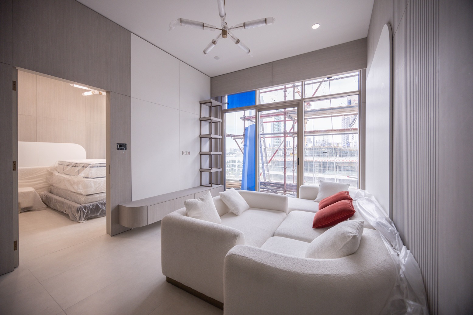 Pearl House By Imtiaz A modern living space featuring a white sofa, a view of construction outside, and minimalistic decor elements.